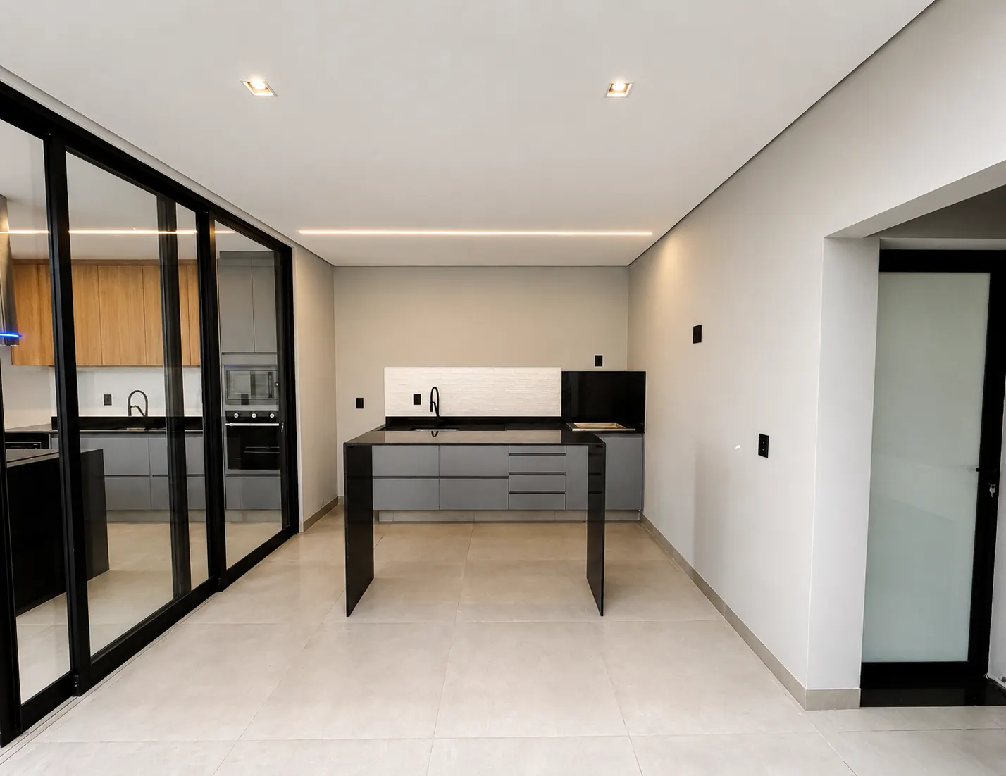 Área gourmet com bancada e portas de vidro